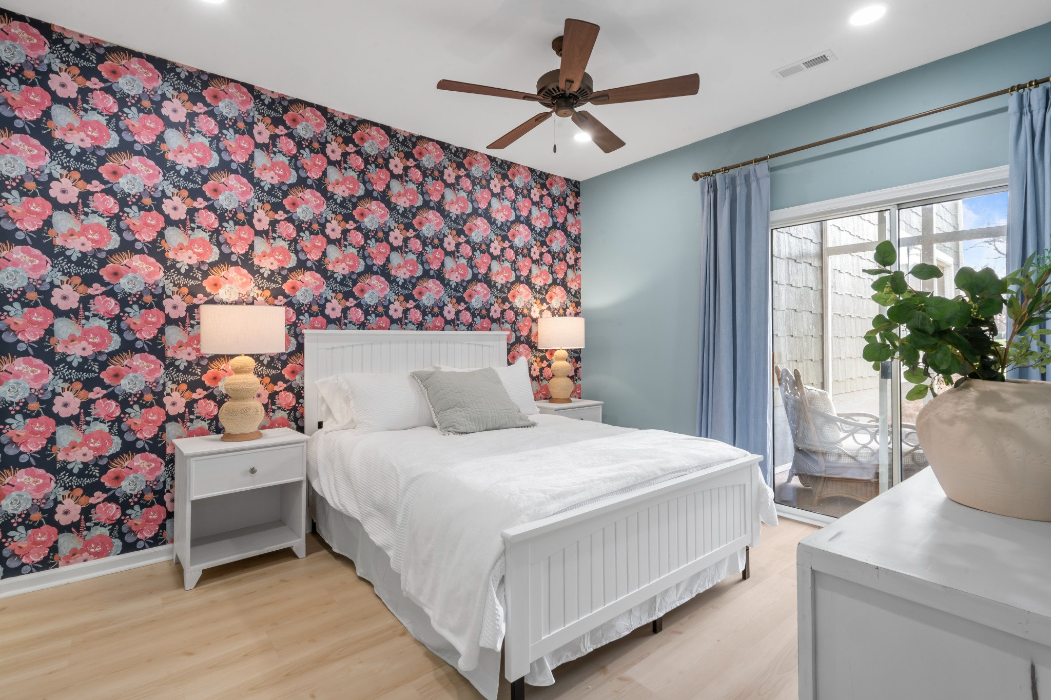 Refined bedroom with floral wallpaper, warm wood tones, and natural light
