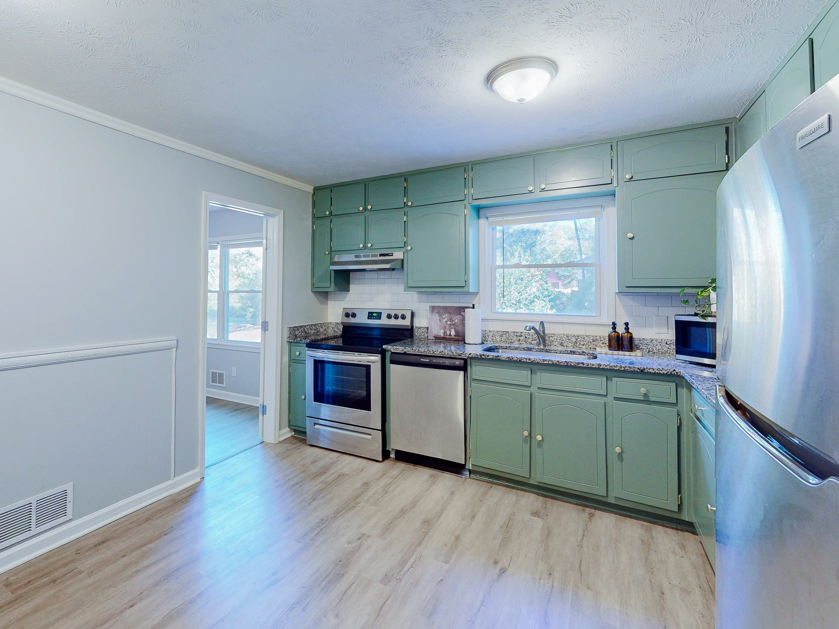 Fresh kitchen with sage cabinetry, stainless appliances, and bright windows